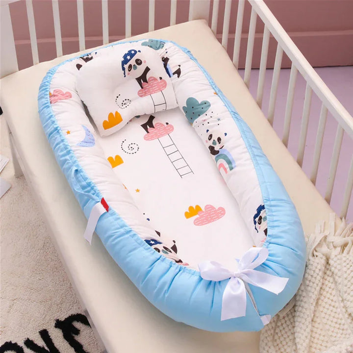 Baby crib with blue and white cushioned baby nest featuring panda and cloud prints, pillow included