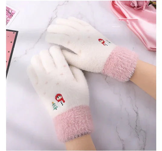 Cozy white gloves with pink cuffs featuring snowman and Christmas tree embroidery on a marble surface