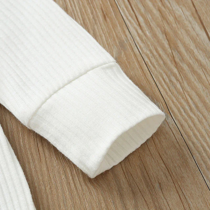Close-up of white ribbed knit sleeve cuff on wooden surface, showcasing fabric texture
