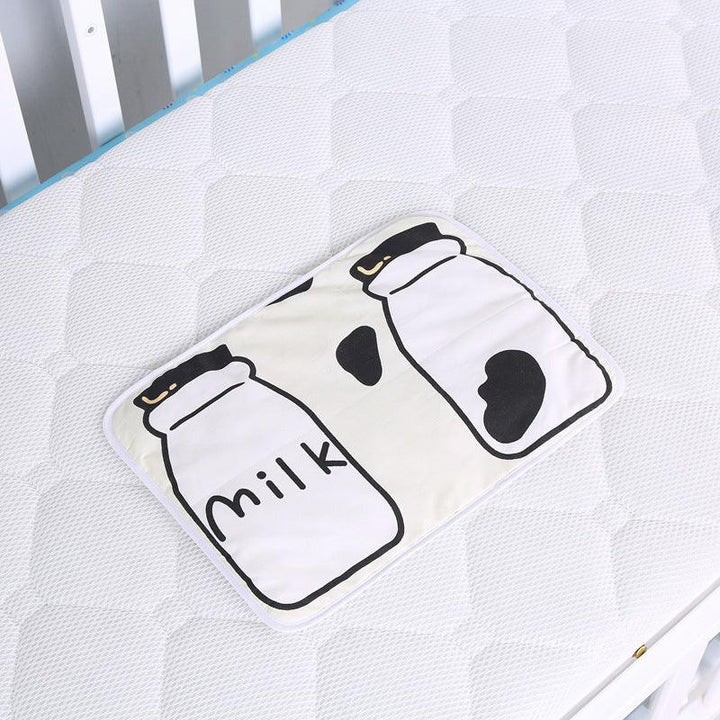 White baby mattress with soft milk bottle design mat placed on top inside white crib
