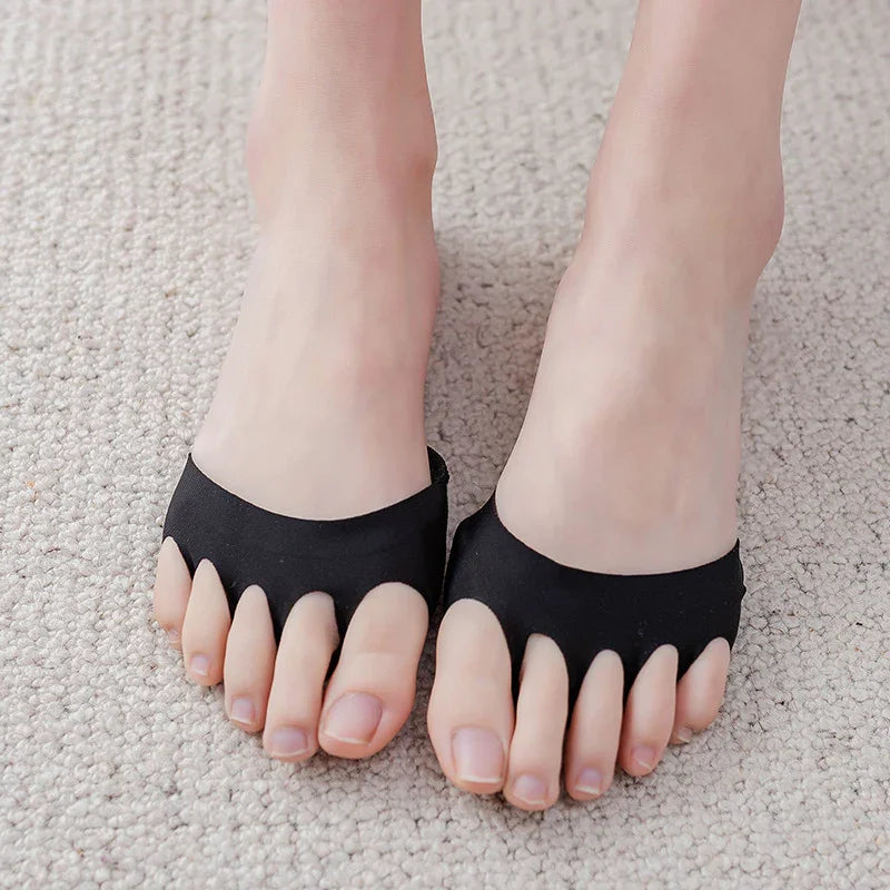 Feet wearing black silicone toe separators on light beige carpet