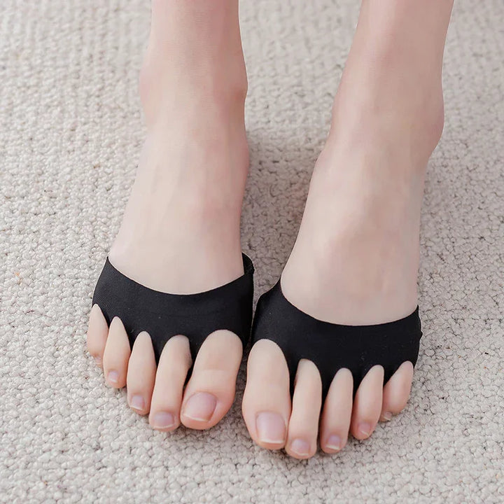 Feet wearing black open-toe foot pads on beige carpet, toe separators visible