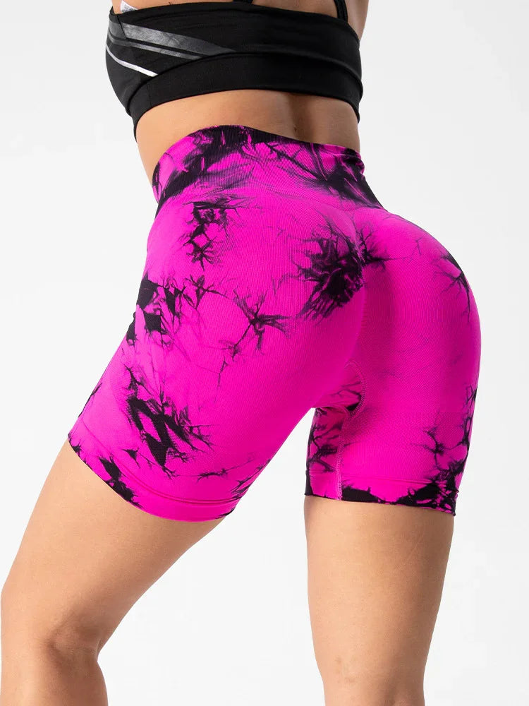 Close-up of woman wearing vibrant pink and black tie-dye high-waisted biker shorts with black crop top