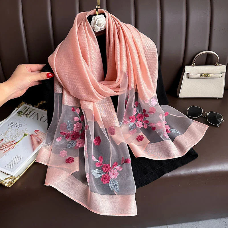 Delicate pink floral embroidered sheer scarf draped on black mannequin with beige handbag and sunglasses