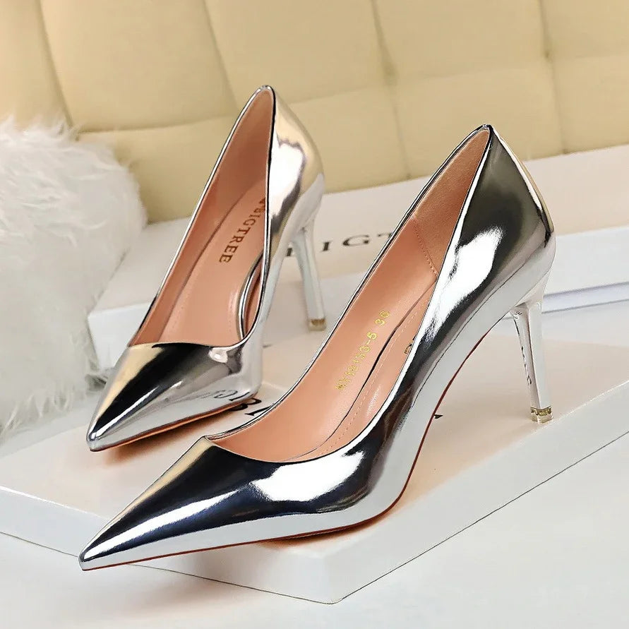 Pair of shiny silver metallic high heel pointed-toe pumps on white surface