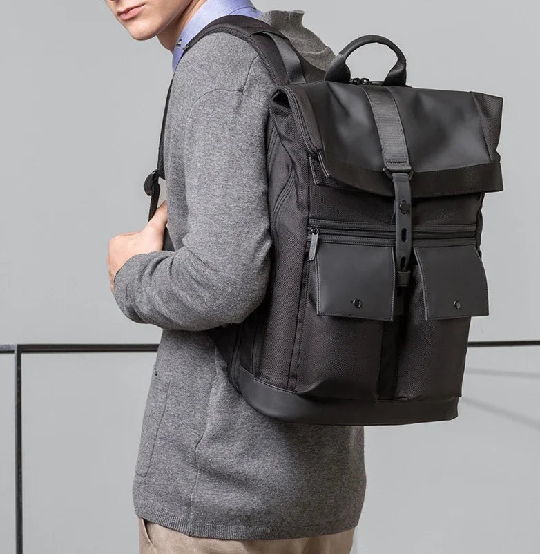 Man wearing gray sweater carrying stylish black backpack with buckle and front pockets