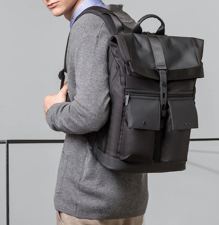 Man wearing gray sweater carrying stylish black backpack with buckle and front pockets