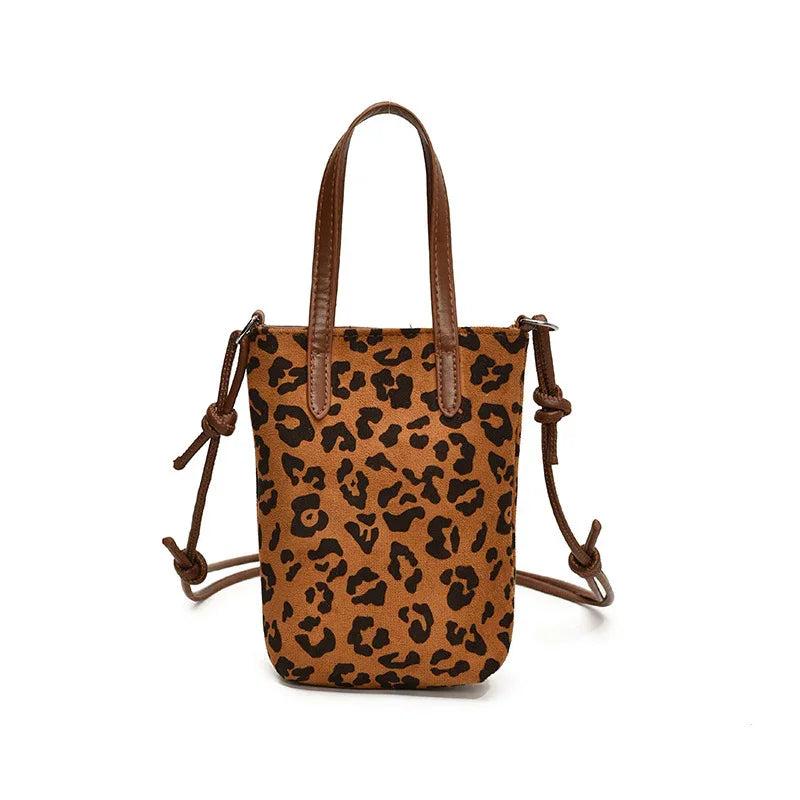 Leopard print tote bag with brown leather handles and adjustable knotted straps on white background