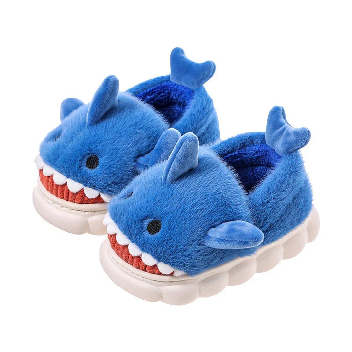 Cozy blue shark-themed plush slippers for kids with fins and teeth details on white soles
