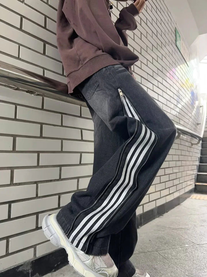 Person wearing black jeans with side zipper and white stripes, paired with white sneakers, standing in subway station