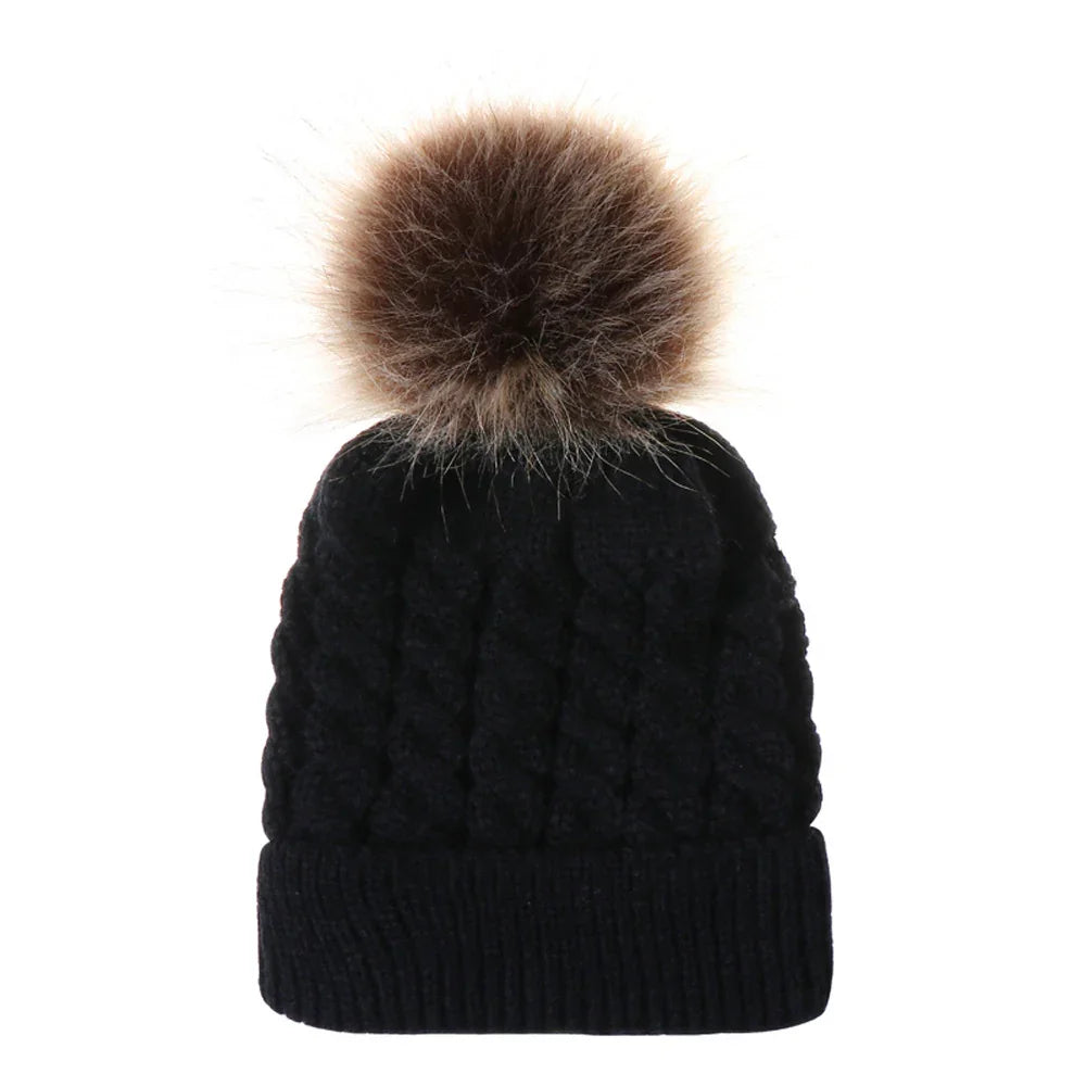 Black cable knit winter beanie with large brown faux fur pom pom on top