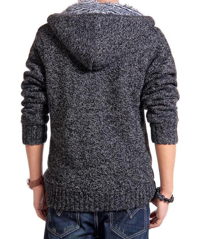 Back view of person wearing dark gray knit hooded sweater with rolled sleeves and blue jeans