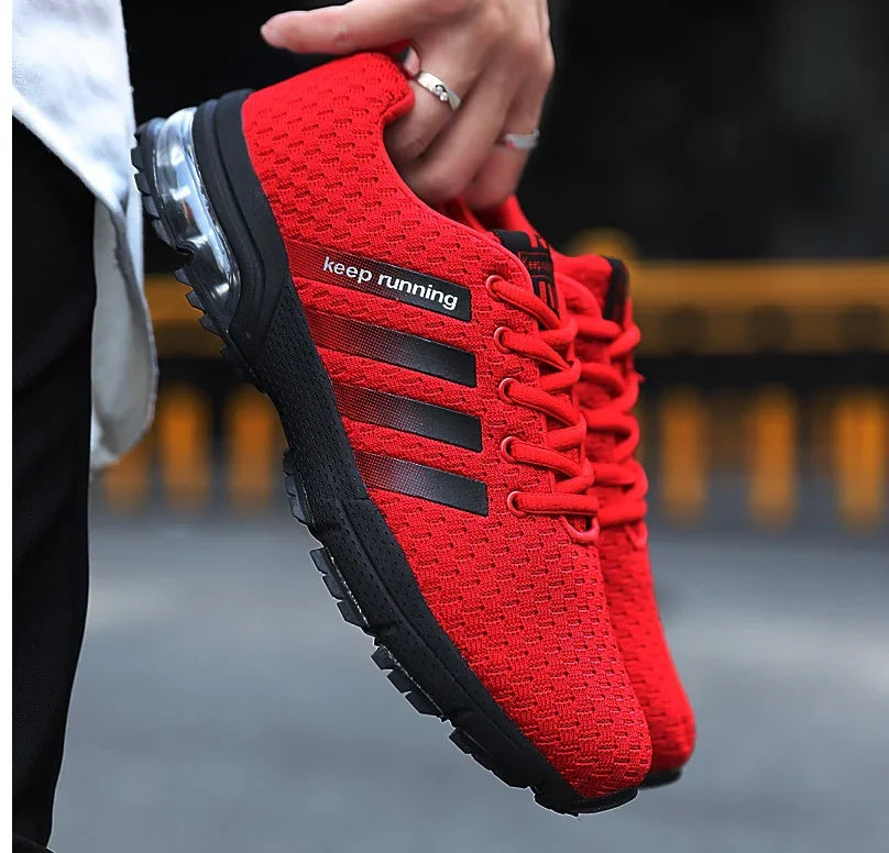 Hand holding red running shoes with black sole and black stripes, featuring keep running text
