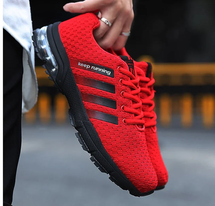 Hand holding red running shoes with black sole and black stripes, featuring keep running text