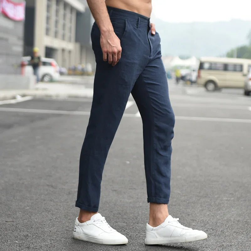 man wearing navy blue slim-fit pants and white sneakers standing outdoors on asphalt