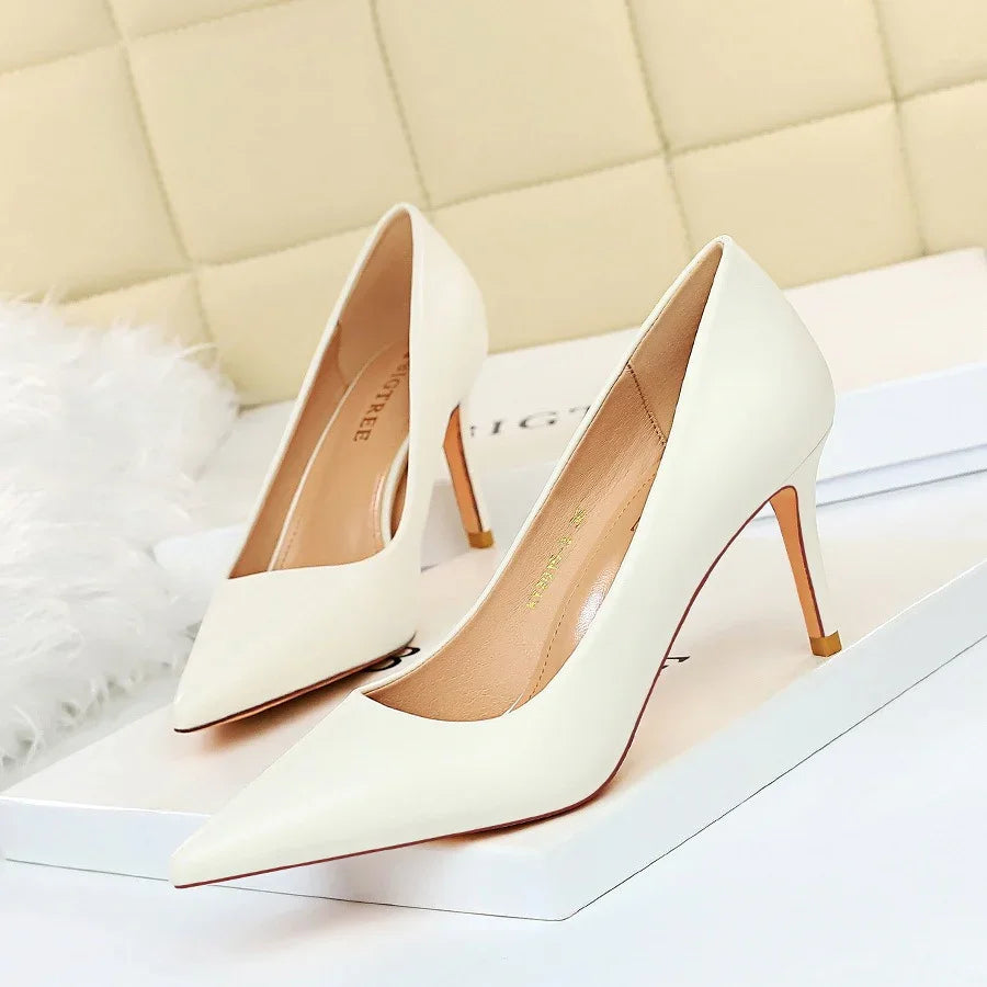 Pair of elegant white pointed-toe high heel pumps on a white box with beige cushioned background