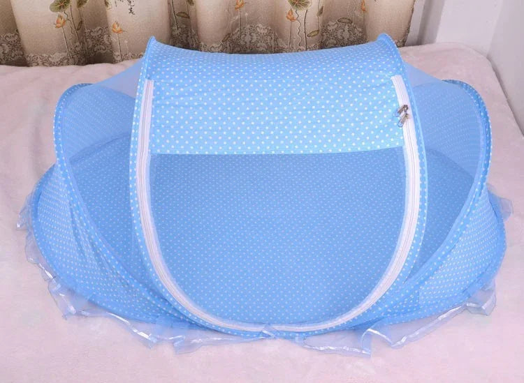 Blue foldable mosquito net with white polka dots on a bed with floral curtains background