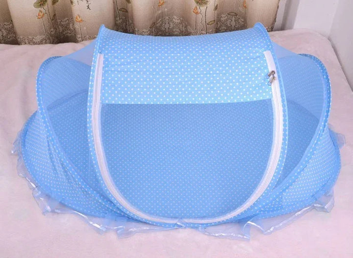 Blue foldable mosquito net with white polka dots on a bed with floral curtains background