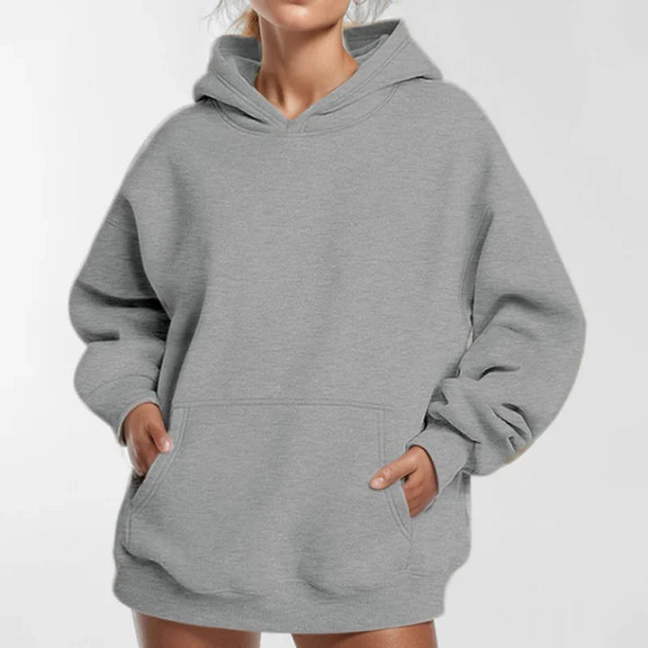 woman wearing oversized gray hoodie with front pocket and long sleeves on white background