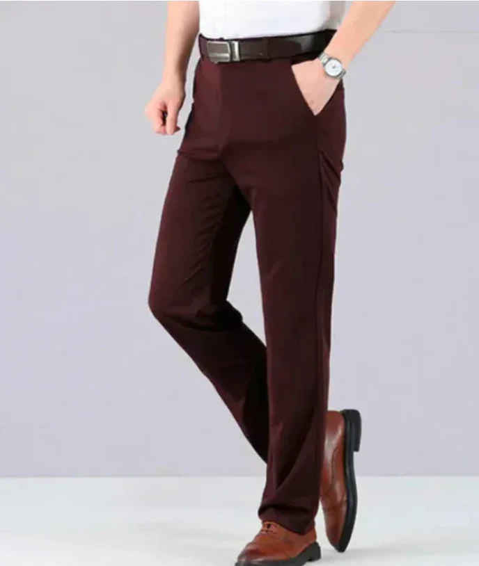 Man wearing dark brown formal trousers with black belt and brown leather shoes on light gray background