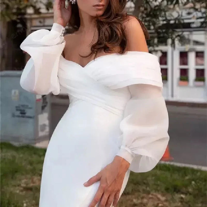 Woman wearing elegant white off-shoulder wedding dress with sheer puff sleeves outdoors