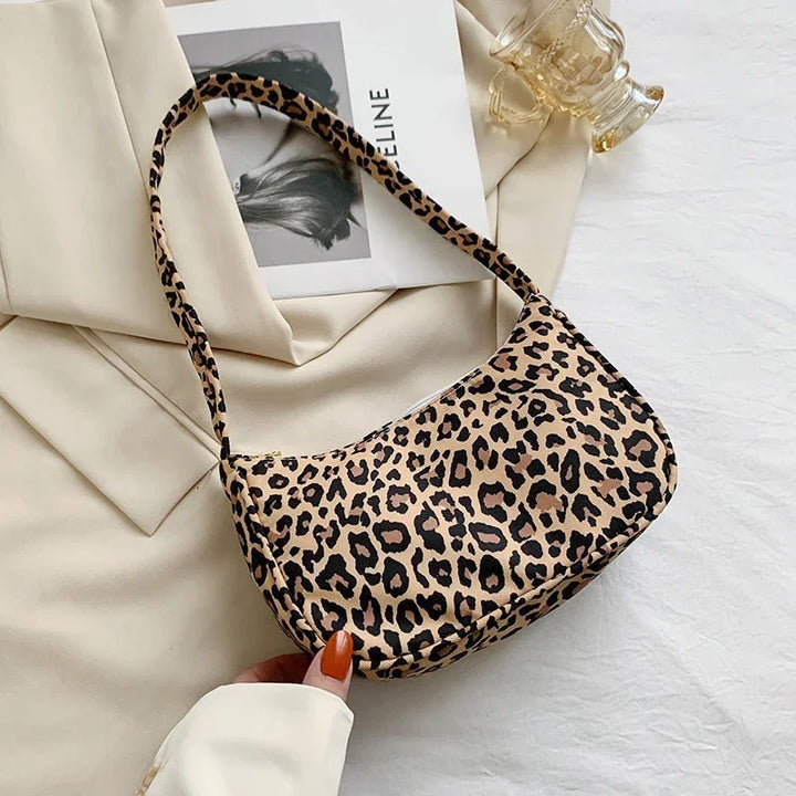 Leopard print shoulder bag on cream fabric with a fashion magazine and glass cup