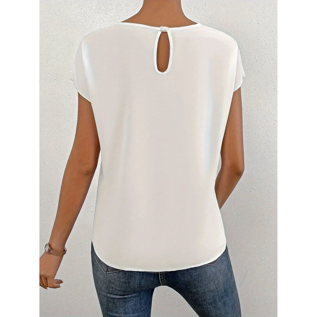 Back view of woman wearing casual white short sleeve top with keyhole button closure and blue jeans