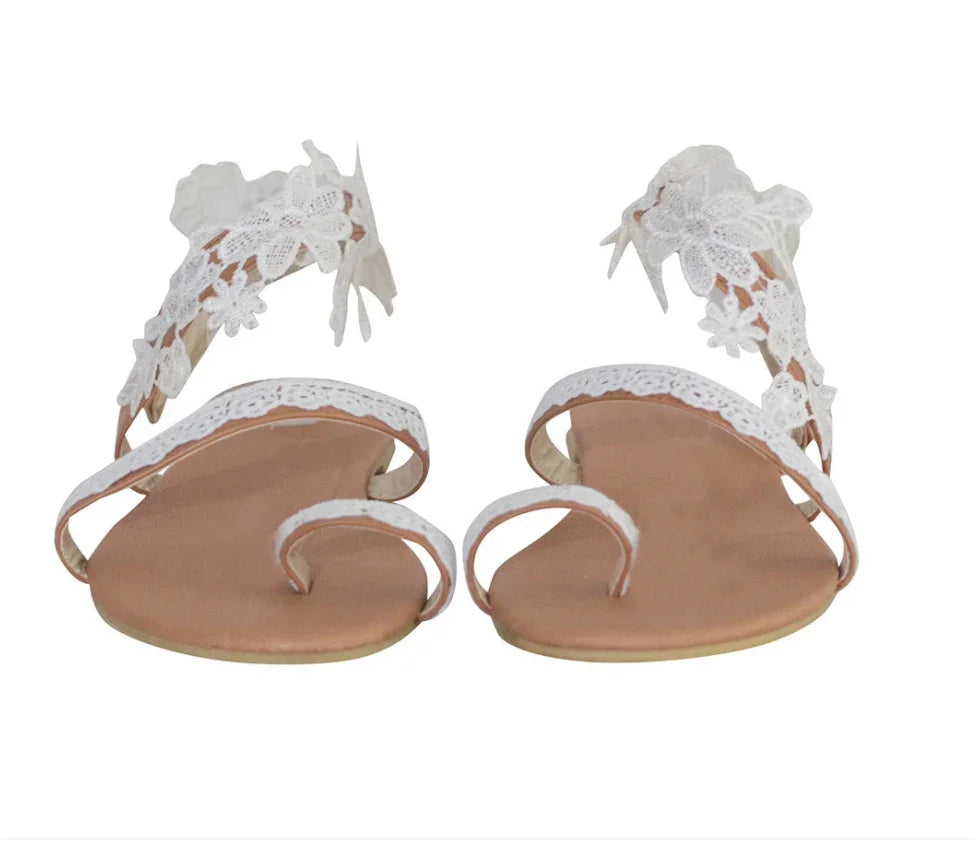White lace floral embellished flat sandals with toe loop and ankle strap on tan sole