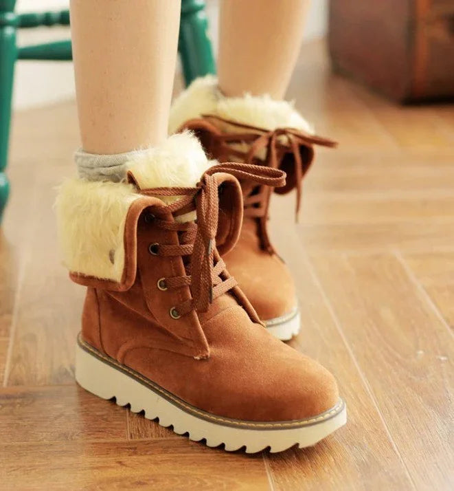 Brown suede winter boots with white fur lining and thick white soles on wooden floor
