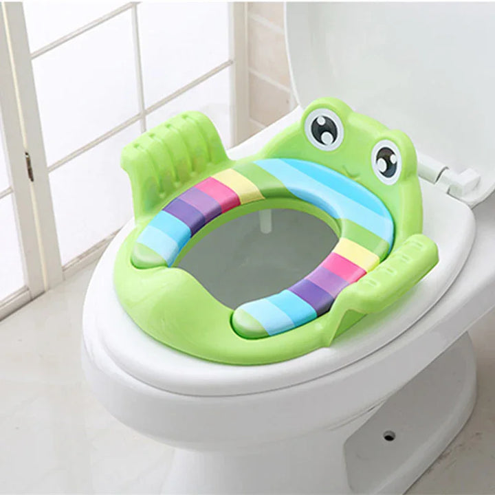 Green frog-themed toddler potty training seat with colorful stripes on white toilet