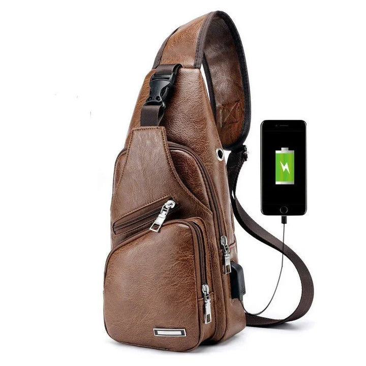 Brown leather sling bag with multiple zip pockets and USB charging port connected to a charging smartphone