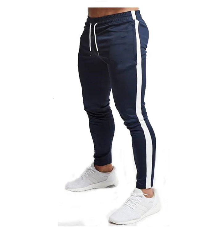 Men's navy blue jogger pants with white side stripes and white drawstring, paired with white sneakers