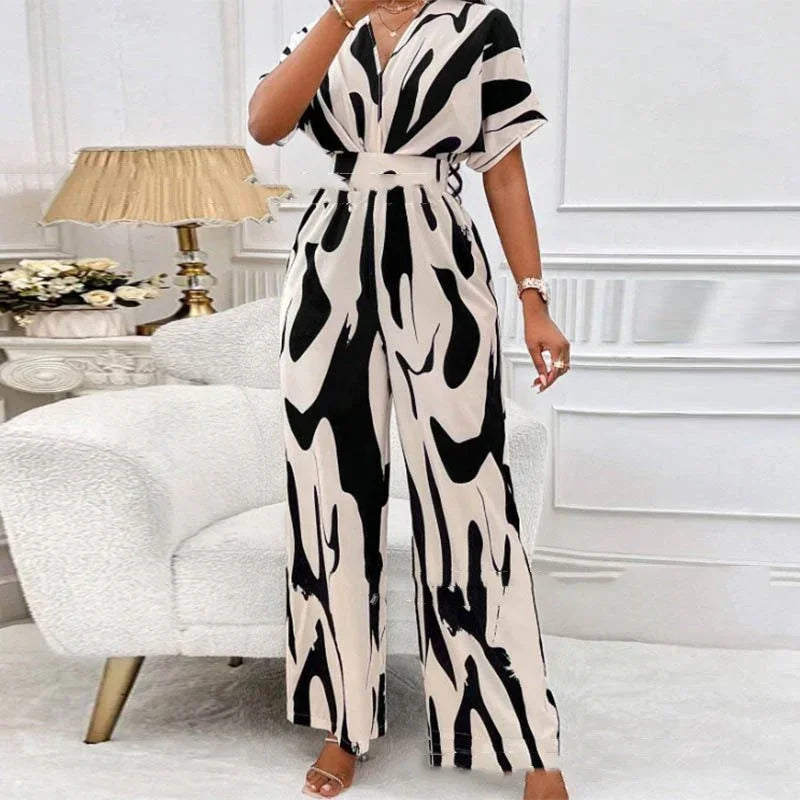 Woman wearing black and white abstract print belted jumpsuit in stylish living room
