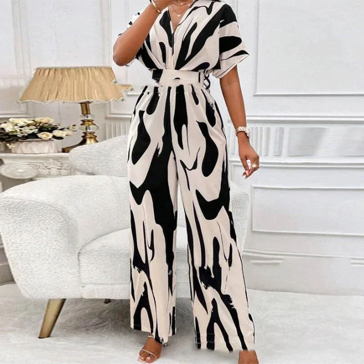 Woman wearing black and white abstract print belted jumpsuit in stylish living room