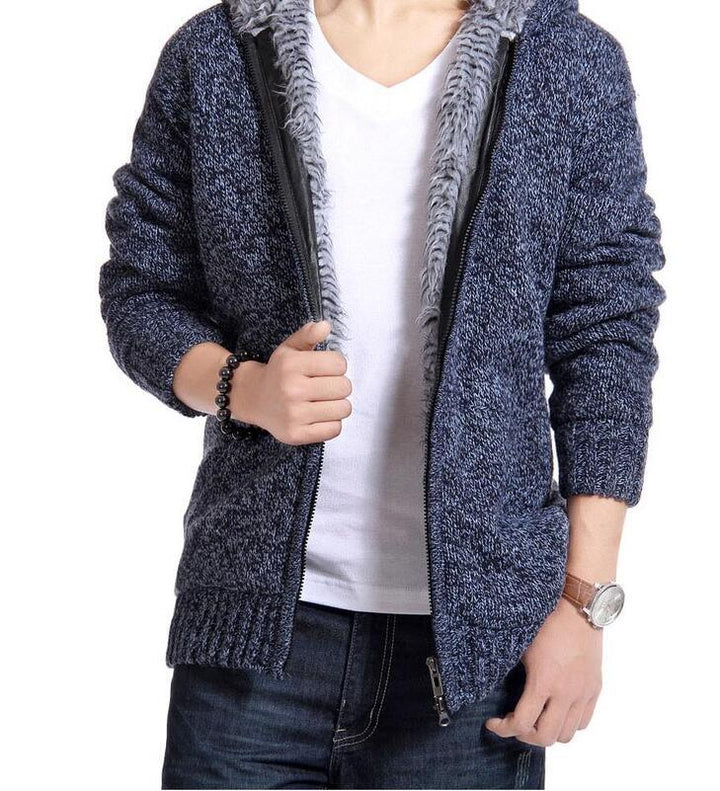 man wearing navy blue knit zip-up hoodie with gray fur lining over white t-shirt and dark jeans