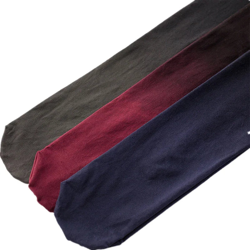 Three pairs of solid color socks in olive green, maroon, and navy blue laid out side by side