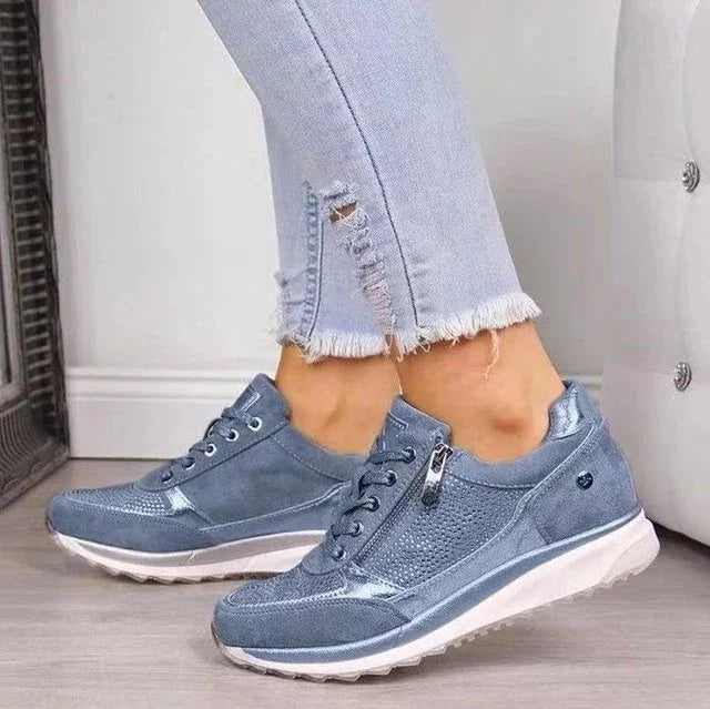 Light blue casual sneakers with side zipper and laces worn with frayed hem jeans on wooden floor