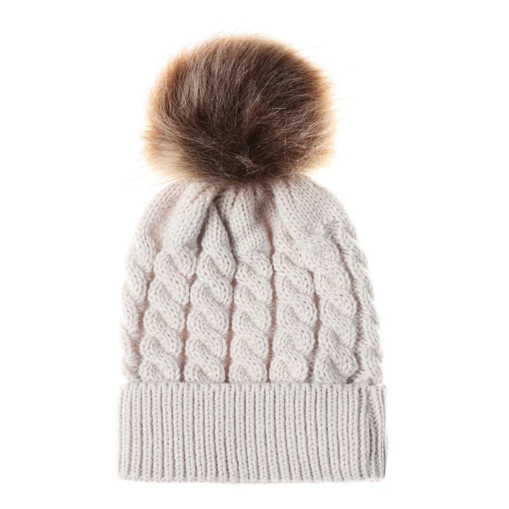 Cream knit winter hat with cable pattern and large brown faux fur pom pom