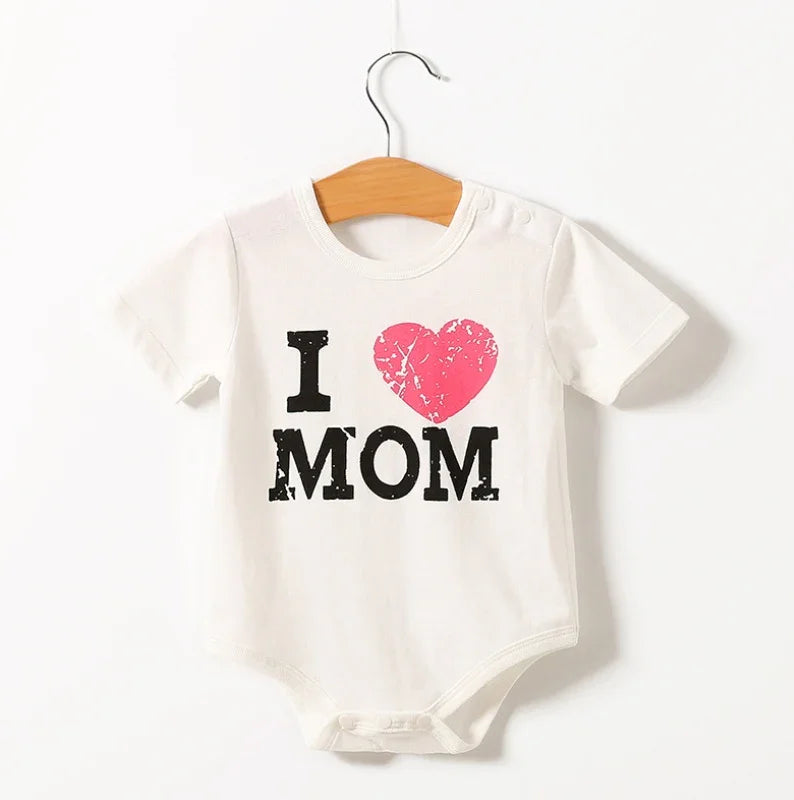 White baby onesie with distressed black text I love MOM and a pink heart, hanging on wooden hanger