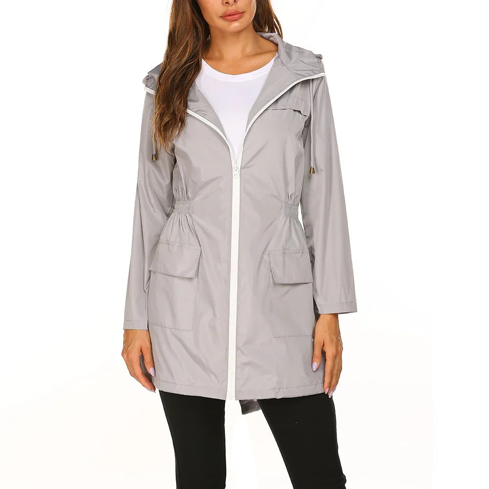Woman wearing light gray hooded zip-up rain jacket with front pockets and white inner shirt