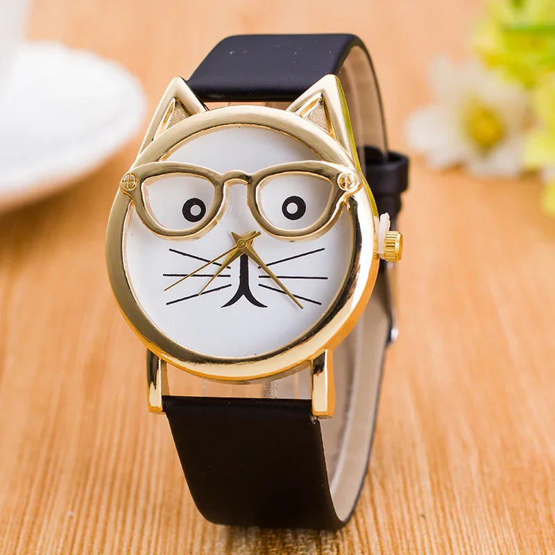 Gold cat face wristwatch with glasses design and black leather strap on wooden surface