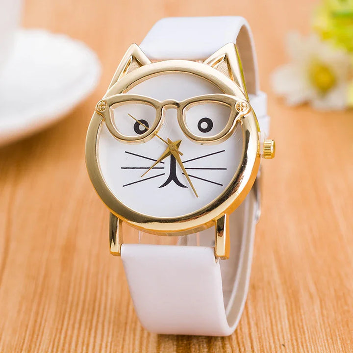 White wristwatch with gold cat-shaped frame and eyeglass design on dial, placed on wooden surface