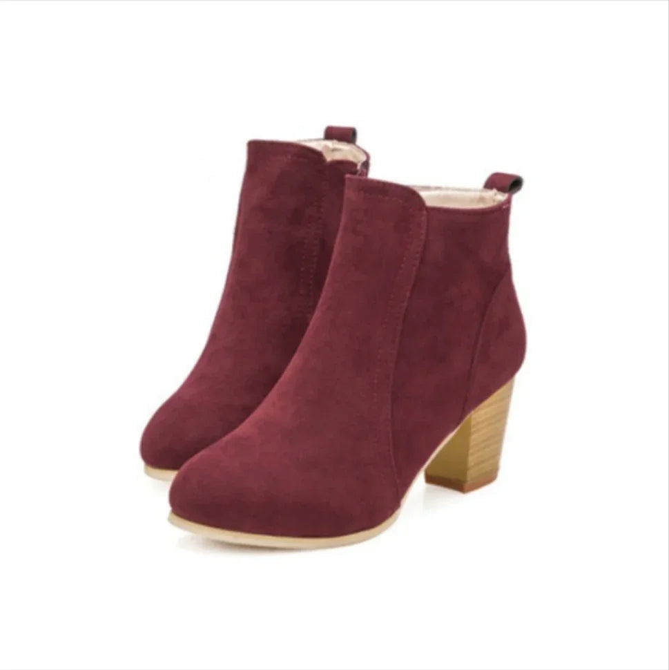 Pair of burgundy suede ankle boots with block heels and beige soles
