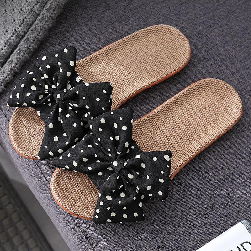 brown woven slippers with black polka dot bows on gray fabric surface