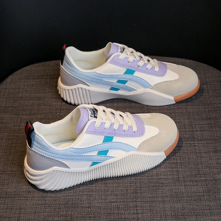 Stylish white and pastel sneakers with purple, blue accents and ribbed rubber soles on gray fabric