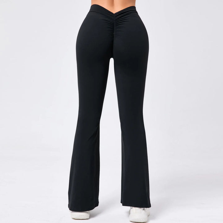 Back view of woman wearing high-waisted black ruched flare yoga pants with white sneakers