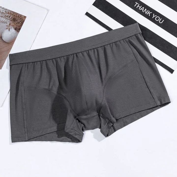 Dark gray men's boxer briefs on white surface with striped thank you card