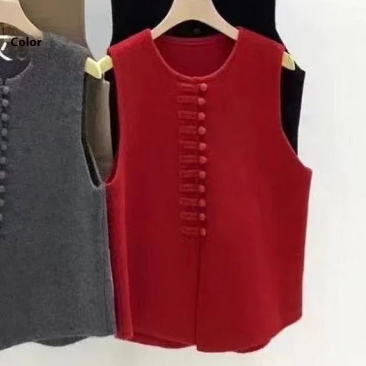 Red sleeveless vest with button detailing hanging on wooden hanger alongside black and gray vests