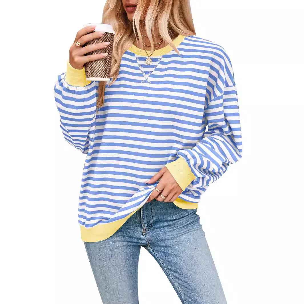 Woman wearing blue and white striped long sleeve shirt with yellow trim, holding coffee cup
