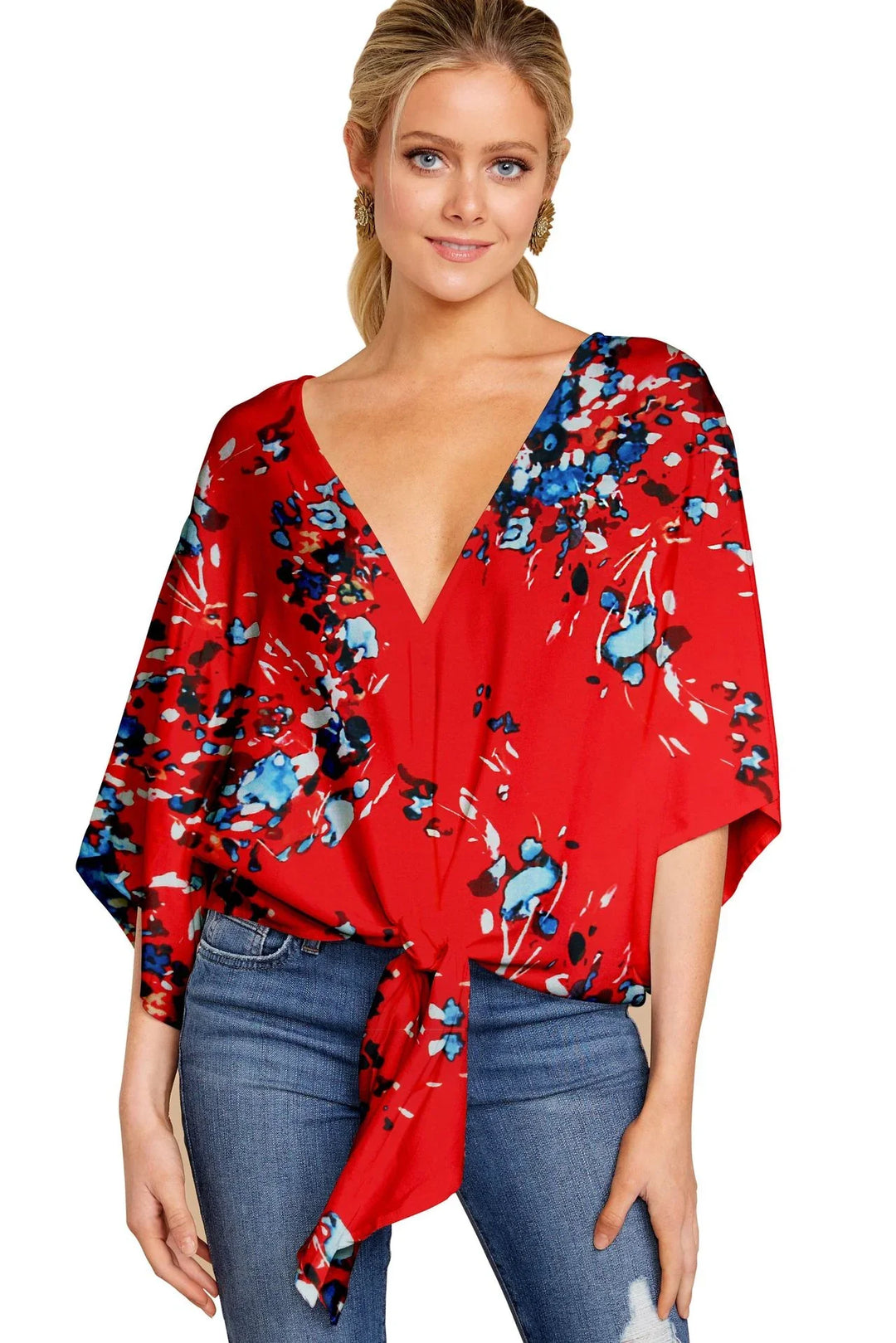 Woman wearing red floral tie-front blouse with deep V-neck and blue jeans